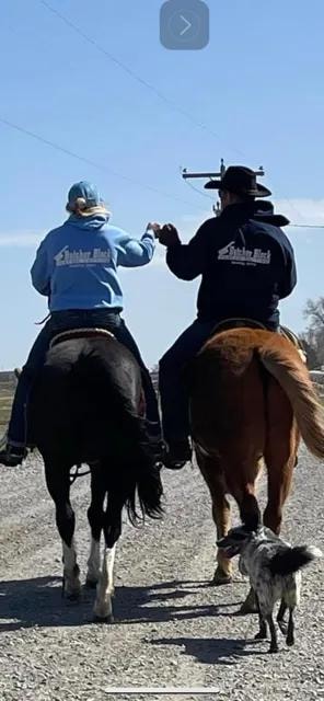 Two Butcher Block riders on horseback wearing branded jackets
